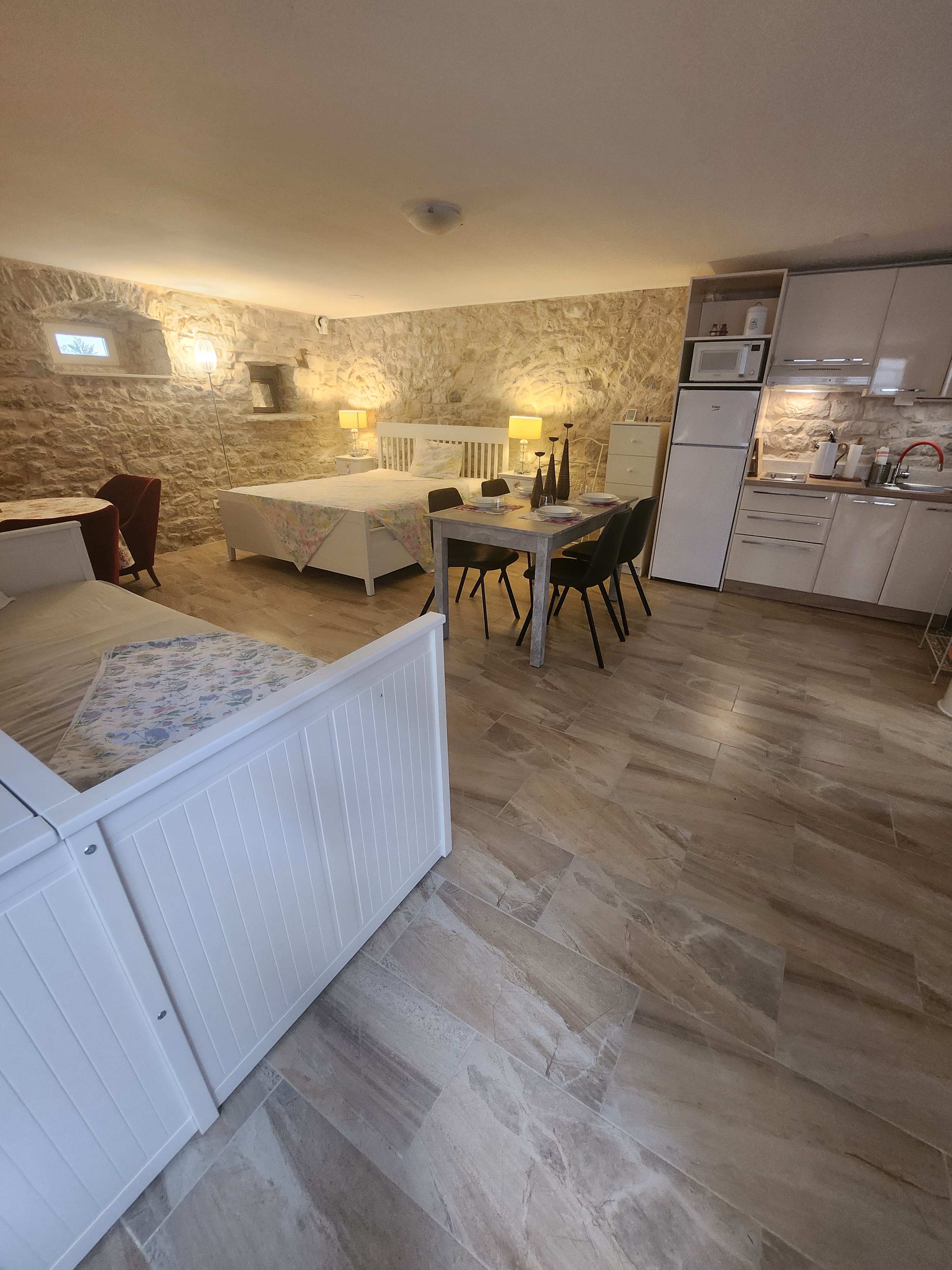 Rodinný studio apartmán — kamenné stěny, dvojlůžko a stolování